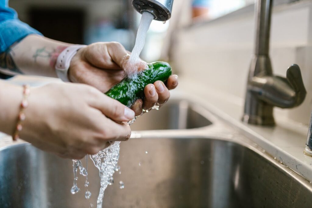 Foto de mulher lavando legume para garantir a segurança do alimento