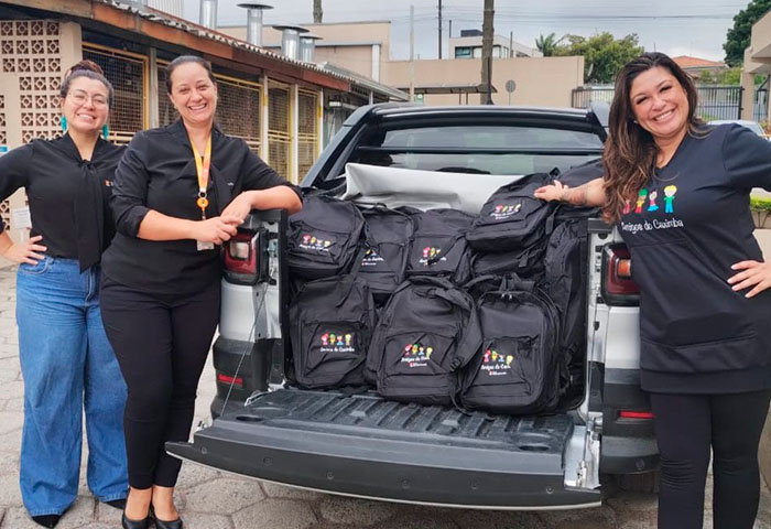 equipe ao lado de mochilas da parceria Risotolândia e Amigos do Caximba